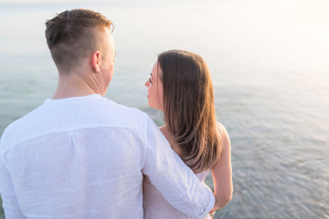 Fototapeta premium Beach couple looking at ocean view from behind. Relaxing on summer travel vacations in tropical destination