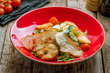 Salad caesar with chicken on red plate