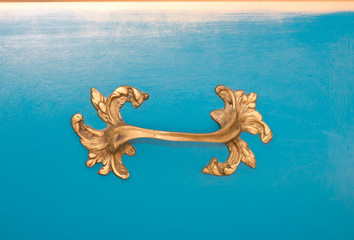Detail of a vintage golden handle on blue background