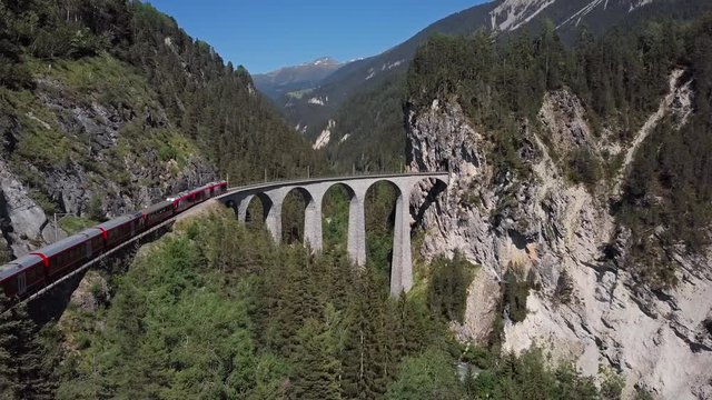 Aerial panorama of Swiss red train on famous Landwasser Viaduct (Landwasserviadukt), Graubunden, Switzerland.