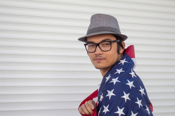 A young guy with glasses and a hat with the flag of the United States of America.