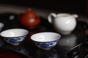 Ceramic tea pot for tea ceremony of red-brown color on a black wooden table for a tea ceremony with white china with blue gzhel