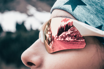 Female model close up face sunglass reflection in winter mountain.