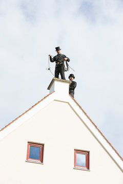 Two Chimney Sweeps Working On House Roof