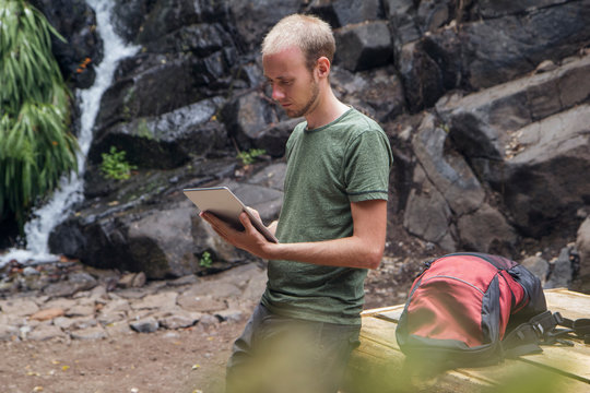 Hiker taking a break at rest area and using tablet, Barranco el Cedro, La Gomera, Canary Islands, Spain