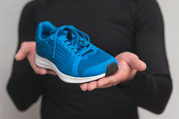 Sportsman is holding in hands a pair of new sport sneakers.