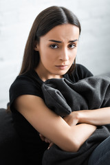 Obraz premium upset young woman hugging pillow and looking at camera while suffering from depression at home