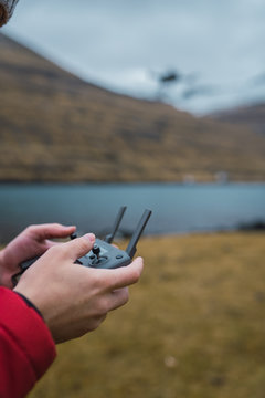 unrecognizable person controling drone near lake in Faroe island