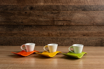 Green, yellow and orange cups of coffee, side view