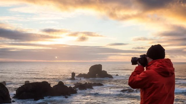 Photographer with a camera is taking pictures during a vibrant and colorful winter sunset. Taken in Ecola State Park near Canon Beach, Oregon Coast, United States of America. Still Image Animation