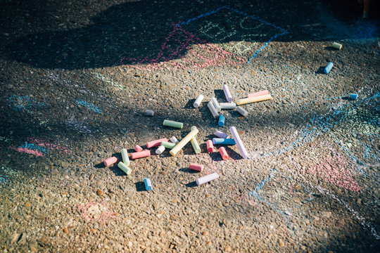 From above red blue green purple chalk and children drawings on asphalt in sunny day