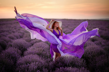 Young happy woman in luxurious purple dress standing in lavender field