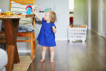 Baby girl in blue dress putting her water bottle on the table