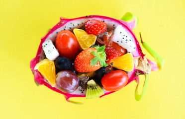 Fruit salad bowl served in a dragon fruit and vegetables healthy organic food strawberries orange kiwi blueberries grape pineapple tomato lemon fresh summer fruits tropical on yellow