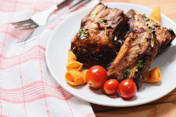 bbq pork ribs grilled with tomatoes herbs and spices on plate served on wooden table - Roasted barbecue pork spare rib sliced