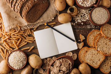 Wholegrain food empty notebook and freshly baked rye bread on table