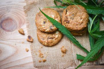 Cookies with cannabis leaf marijuana herb on sack wooden background - cannabis food snack for health