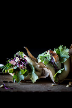 From above row of Gua Bao sandwiches in lotus leaf bread filled with bacon and parsley served on wooden board
