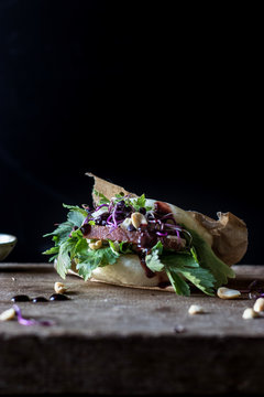 From above row of Gua Bao sandwiches in lotus leaf bread filled with bacon and parsley served on wooden board