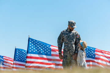 selective focus of military man in cap looking at kid and american flags