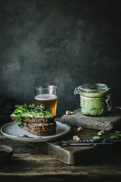 Toasts with green cashew pate and slices of cucumber on wooden board