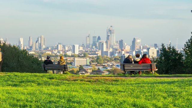 People have rest and enjoy the London skyline from the top of Parliament Hill, in Hampstead Heath, time lapse. London, UK.