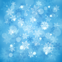 Christmas blurred background of complex defocused big and small falling snowflakes in light blue colors with bokeh effect