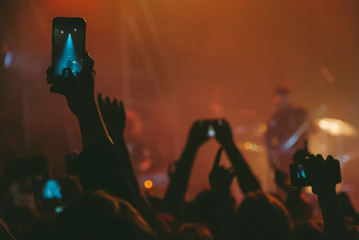 Raised up hands with cellphones recording videos from music show