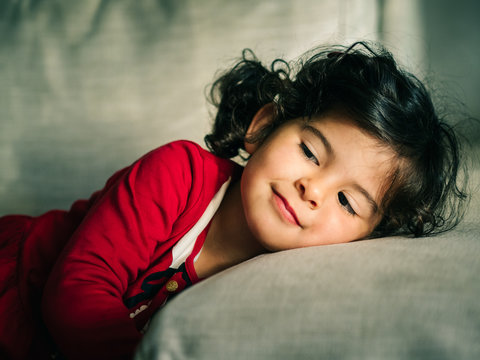 Girl in red dress resting on pillow at home