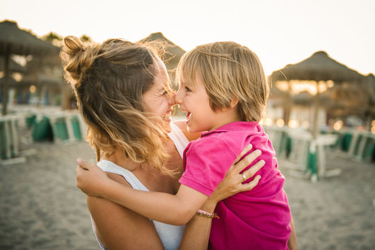 Smiling mother and son rubbing noses while standing on beach