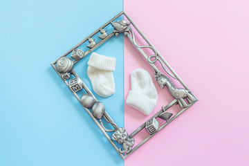 Baby photo frame and  baby socks on blue and pink background. Motherhood concept. Guessing unborn baby gender Girl or boy. Top view, layout, flat lay composition. Copy space for text.