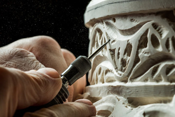 Crop hands carving ornament on plaster