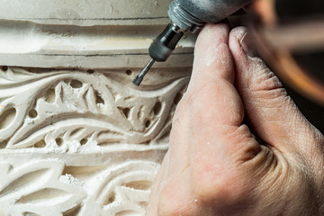 Crop hands carving ornament on plaster