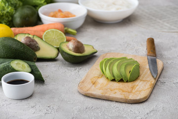 cut avocado on cutting board with knife among raw ingredients