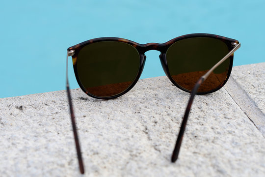 Paire de lunette de soleil au bord d'une piscine.