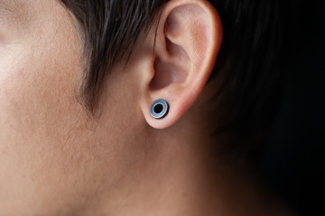 piercing in the ear, tunnels in the ears of a young man lifestyle