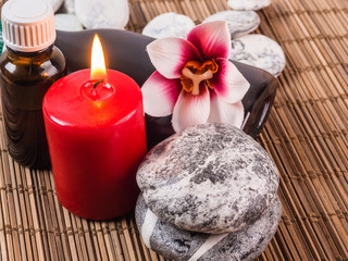 Obraz na płótnie Canvas Spa background with red candle, massage oils and stones