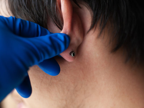 piercing and stretching the ears with medical  blue gloves. increase the diameter of the ear tunnels