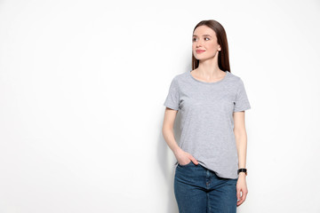 Fototapeta premium Young woman in t-shirt on light background. Mock up for design