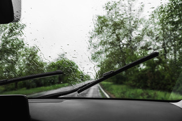 Blurred view of suburban road through wet car window. Rainy weather