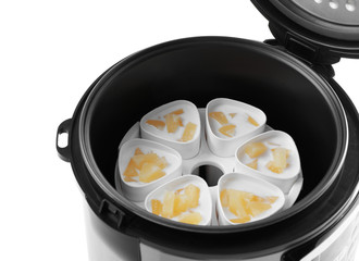 Cups of pineapple yogurt in multi cooker on white background, closeup