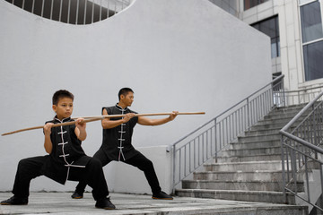 Son and father are engaged in Wushu. Morning Wushu training in the city.