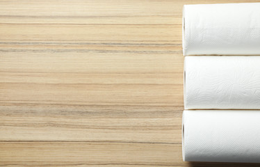 Rolls of paper towels on wooden table, top view. Space for text