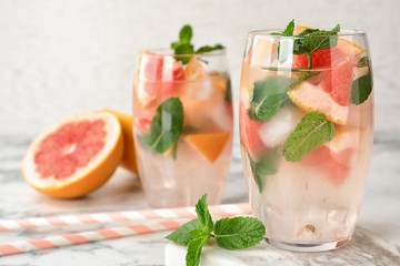 Glasses of refreshing drink with grapefruit and mint on marble table, space for text