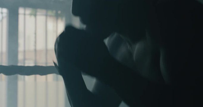 Cinematic shot of a professional young muscular shirtless african man is practicing shadow boxing work out in a gym with ring. 