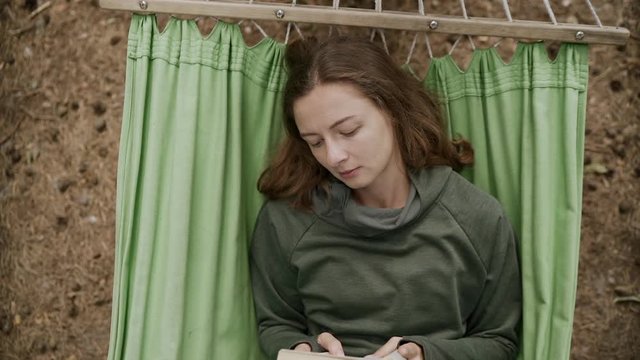 Single woman reading a book in hammock. Slow motion