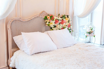 Beautiful luxury classic white bright clean interior bedroom in baroque style with king-size bed, large window, armchair and flower composition
