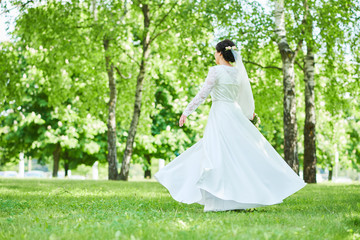 bride in wedding dress dancing in park