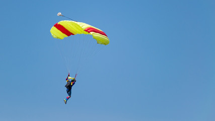 jump with a tandem colored parachute on a blue sky with white clouds, adrenaline and risk.