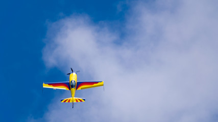 an acrobatic plane, flying in the blue sky with white clouds, doing acrobatics